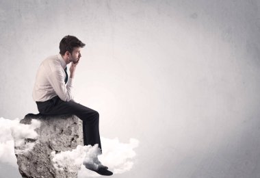 Ofis çalışanı kayanın tepesinde oturuyor.