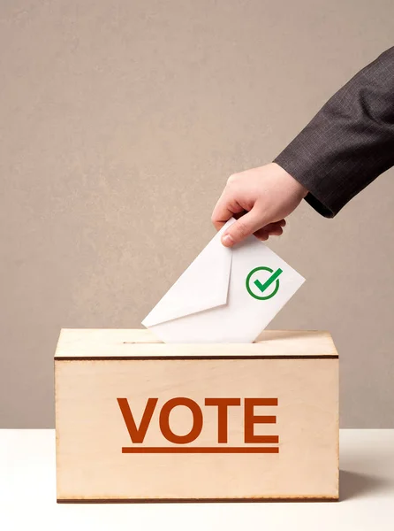 Close up of male hand putting vote into a ballot box