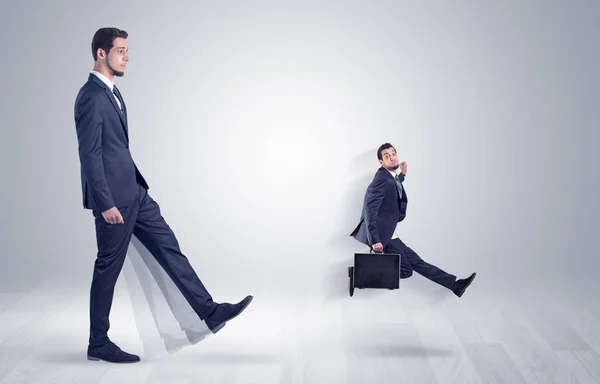 Giant businessman kicking out little businessman — Stock Photo, Image