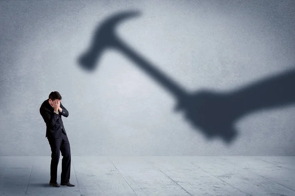 Business person afraid of a shadow hand holding hammer concept — Stock Photo, Image