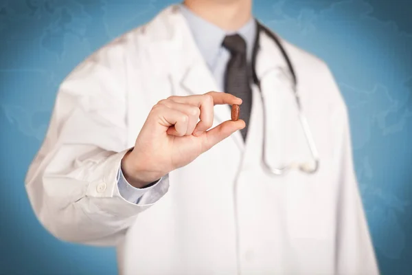 Доктор в білому тримає таблетку — стокове фото