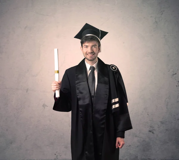 Portret van een jonge afgestudeerde student op grungy achtergrond — Stockfoto