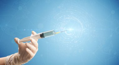 Kadın doktor elinde şırınga tutuyor.