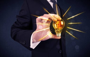 bir elektrik ampulü tutan iş kişi