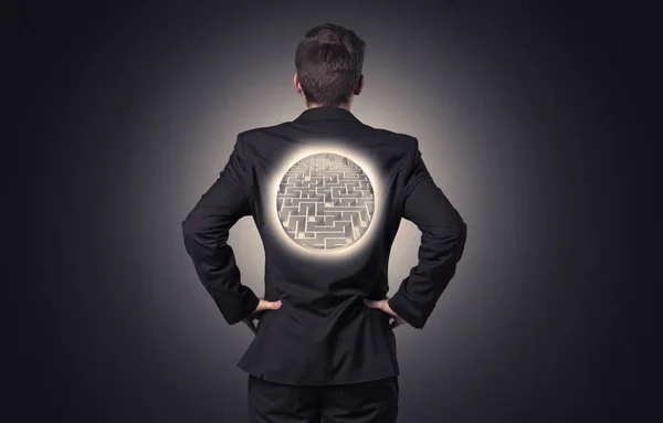 Бизнесмен стоит с лабиринтом на спине — стоковое фото