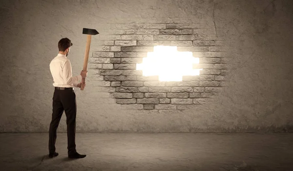 Business man hitting brick wall with hammer and opening a hole — Stock Photo, Image