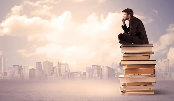 Homme assis sur une pile de livres au-dessus de la ville — Photo