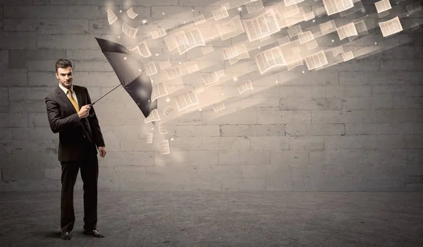 Homem de negócios protegendo com guarda-chuva contra o vento de papéis — Fotografia de Stock