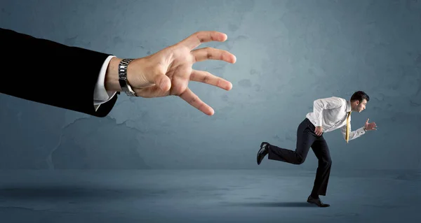 Hombre de negocios huyendo de un concepto de mano enorme — Foto de Stock