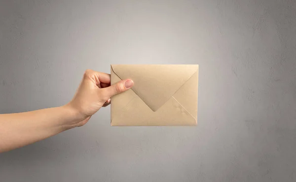 Hand holding envelope with empty wall background — Stock Photo, Image