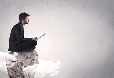 Ofis çalışanı kayanın tepesinde oturuyor.