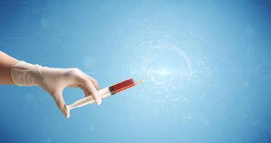 Kadın doktor elinde şırınga tutuyor.