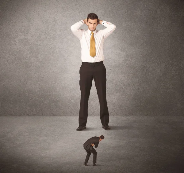 Büyük iş adamı küçük işçilere bakıyor.