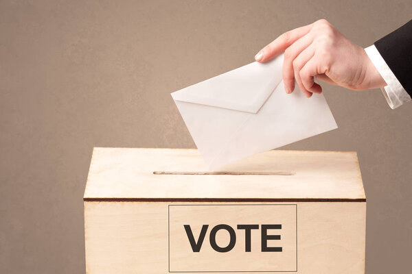 Крупный план мужской руки, помещающей голоса в урну для голосования
