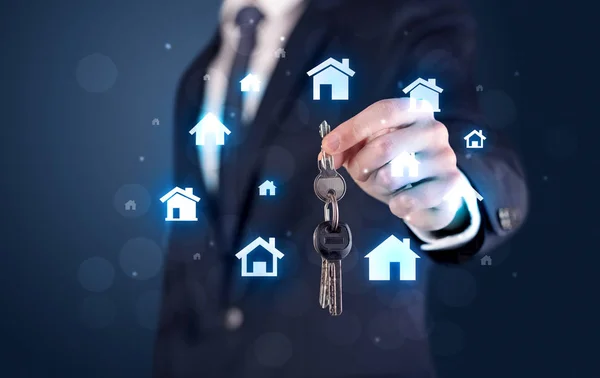 Бізнесмен тримає ключі з будинками навколо — стокове фото