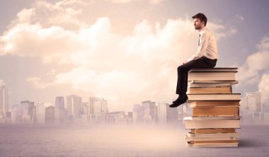 Şehrin üstündeki kitap yığınında oturan adam.