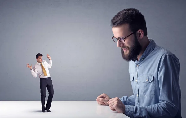 Giovane uomo d'affari che lotta con uomo d'affari in miniatura — Foto Stock