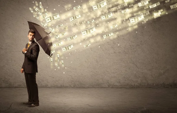 Hombre de negocios sosteniendo paraguas contra concepto de lluvia dólar — Foto de Stock