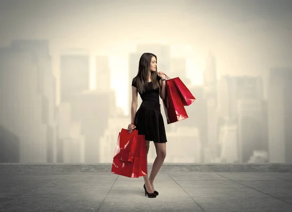 Elegante chica de ciudad con bolsas de compras rojas —  Fotos de Stock