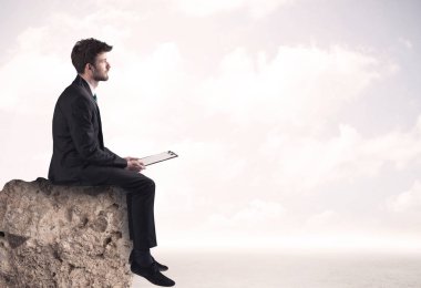 İş adamı taşın üstünde oturuyor.