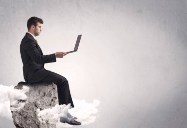 Ofis çalışanı kayanın tepesinde oturuyor.