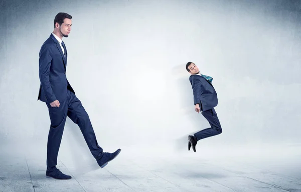 Big businessman kicking small businessman — Stock Photo, Image