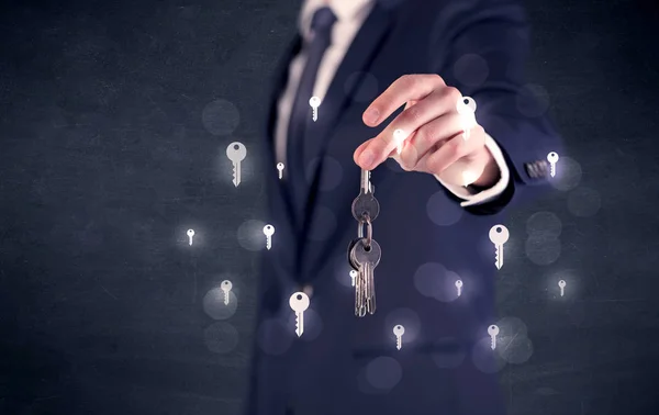 Podnikatel, drží klíče s klíči a okolí — Stock fotografie