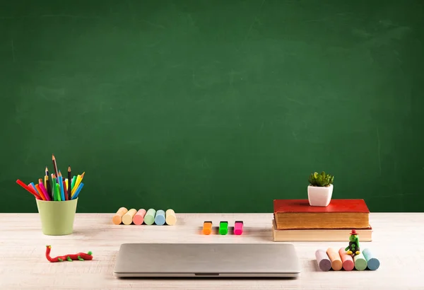 Schoolspullen op bureau met leeg schoolbord — Stockfoto