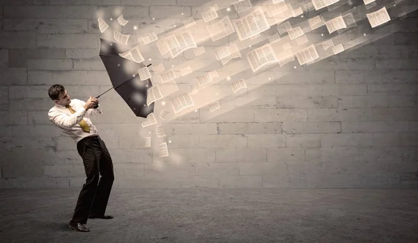 Business man protecting with umbrella against wind of papers — Stock Photo, Image