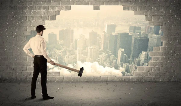 Hombre de negocios golpeando la pared con martillo en la vista de la ciudad — Foto de Stock