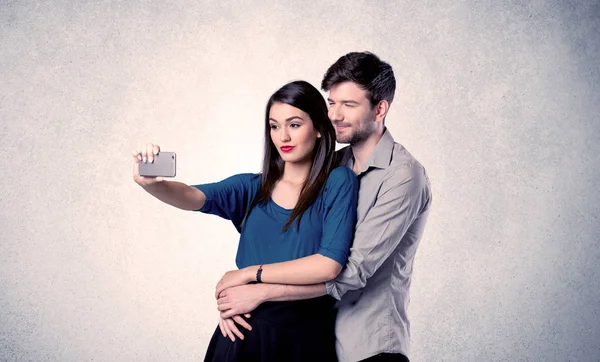 Pareja feliz tomando selfie con pared clara —  Fotos de Stock