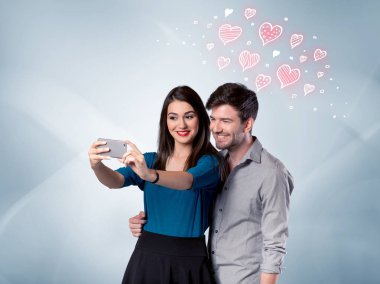 Aşık çift kırmızı kalple selfie çekiyor.