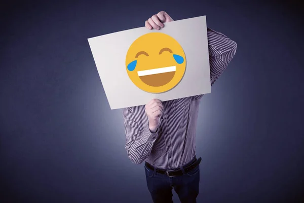 Empresario sosteniendo papel con emoticono risueño —  Fotos de Stock