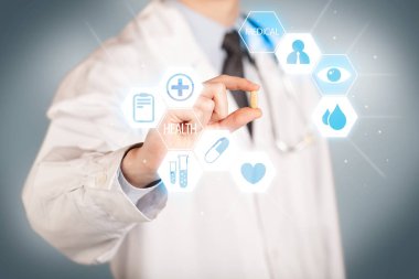 Beyazlı bir doktor elinde hap tutuyor.