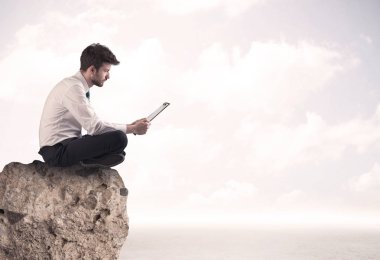 İş adamı taşın üstünde oturuyor.