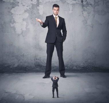 Büyük işletme zorbası küçük iş arkadaşına bakıyor.