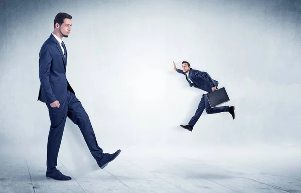 Big businessman kicking small businessman — Stock Photo, Image