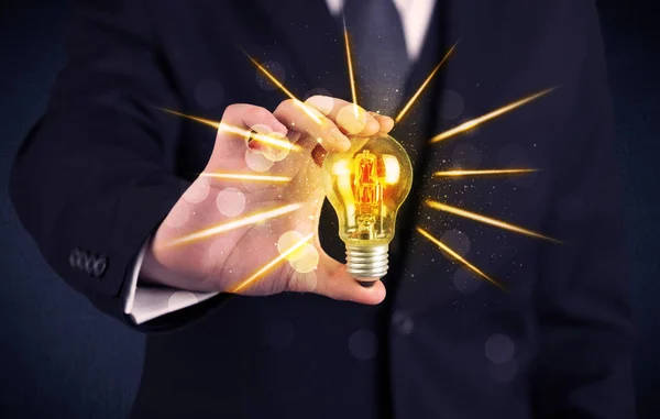 Business person holding an electric light bulb — Stock Photo, Image