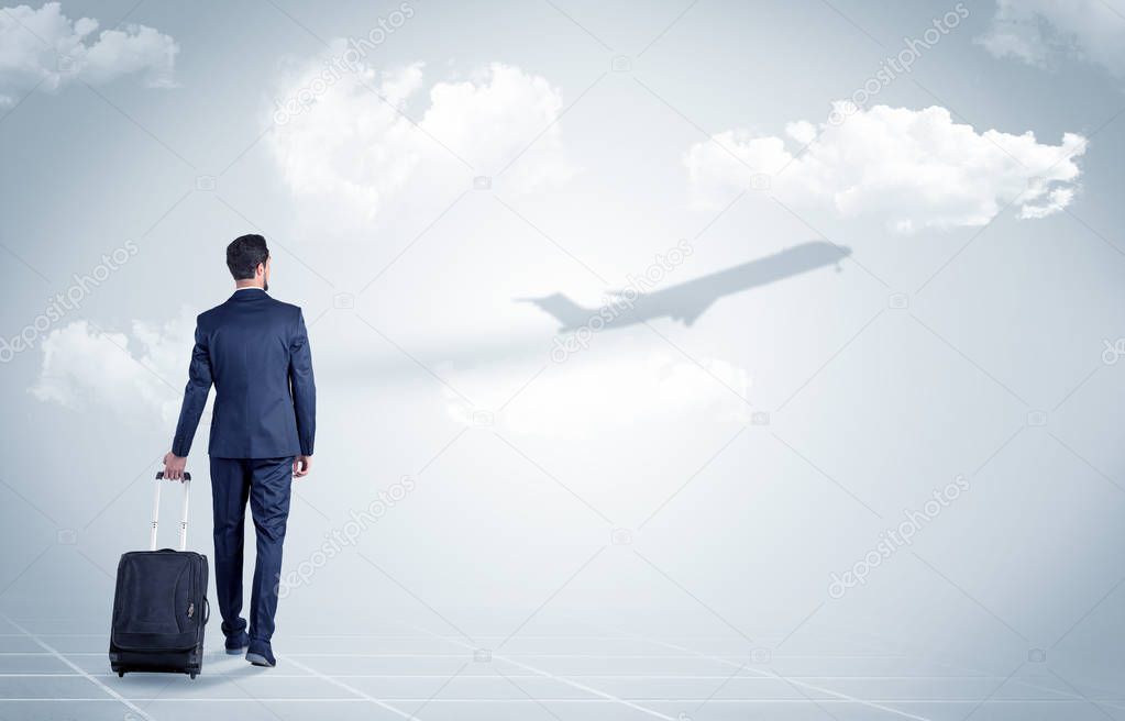 Businessman with luggage  look to an airplane