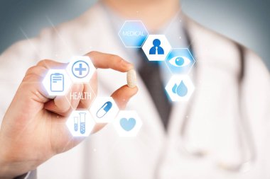 Beyazlı bir doktor elinde hap tutuyor.