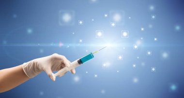 Kadın doktor elinde şırınga tutuyor.