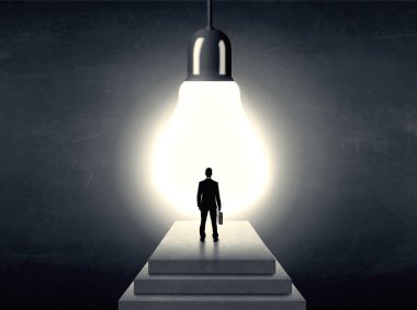 Bir adım önünde büyük bir ampul üzerinde duran adam