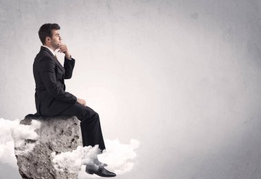 Ofis çalışanı kayanın tepesinde oturuyor.