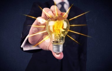 bir elektrik ampulü tutan iş kişi