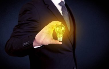 parlak sarı ampul tutan takım elbiseli adam