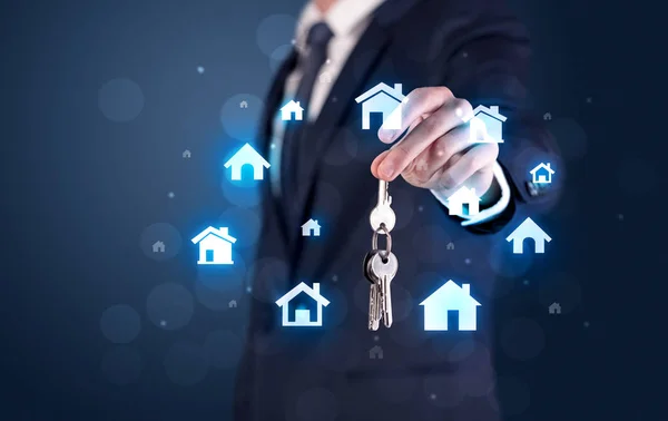 Geschäftsmann hält Schlüssel mit Häusern herum — Stockfoto