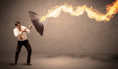 İş adamı kendini bir umbrell ile bir yangın oka savunmak