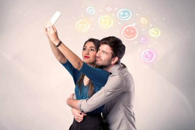 Mutlu çift gülen yüzle selfie çekiyor.