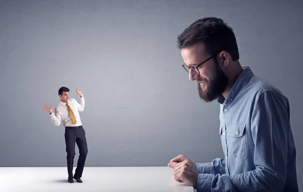 Joven hombre de negocios luchando con empresario en miniatura —  Fotos de Stock