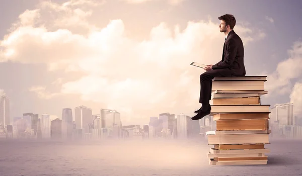 Hombre de negocios con portátil sentado en los libros — Foto de Stock